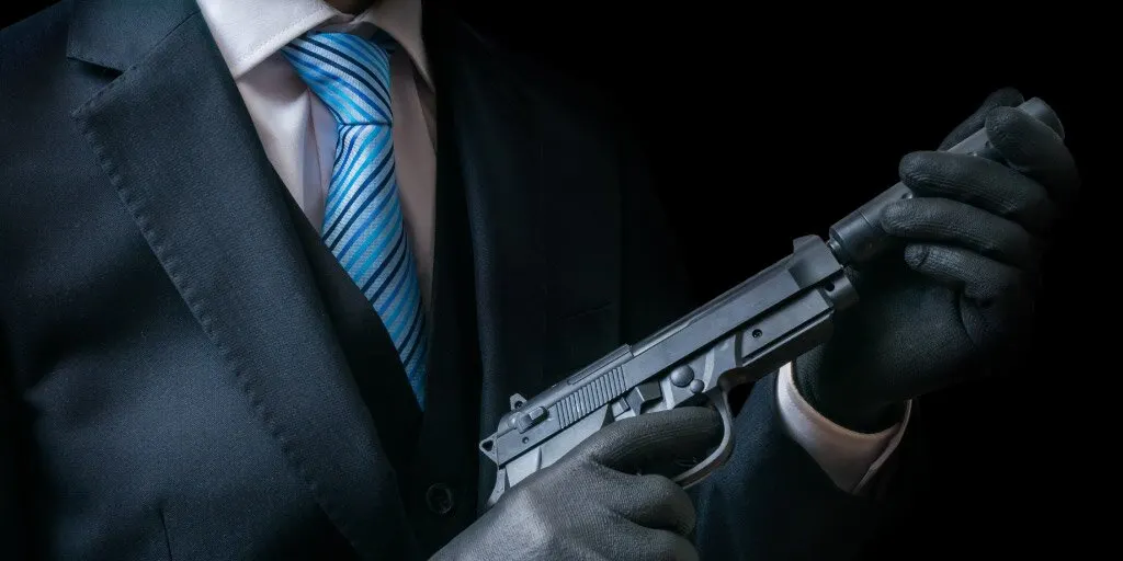 James Bond in black suit attaching silencer to firearm